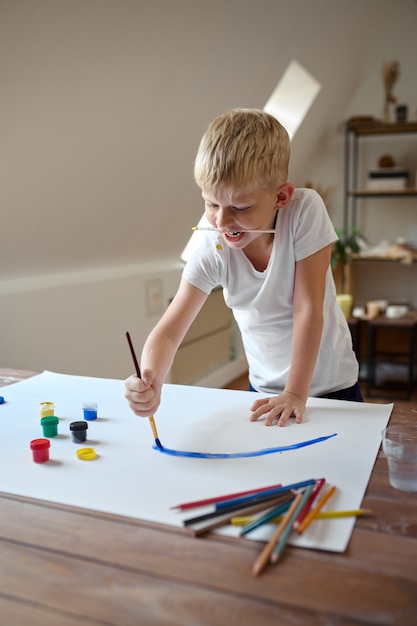 Kleiner Junge, der mit Gouache auf seinem Gesicht zeichnet