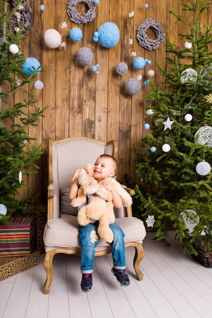 Kleiner Junge, der mit Spielzeug zu Hause nahe dem Weihnachtsbaum spielt.