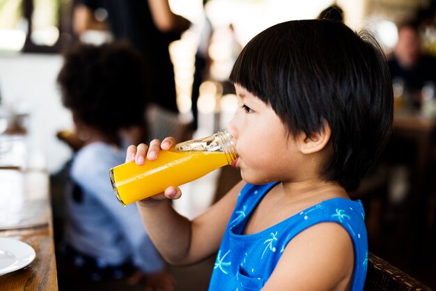 Kleiner Junge, der Orangensaft trinkt