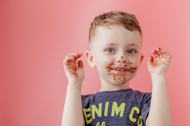 Kleiner Junge, der Schokolade isst Netter glücklicher Junge, der mit Schokolade um seinen Mund verschmiert ist Kinderkonzept