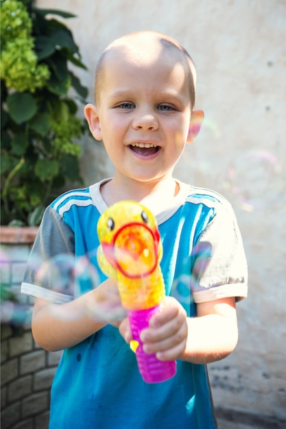 Kleiner Junge, der Seifenblasen im Garten tut