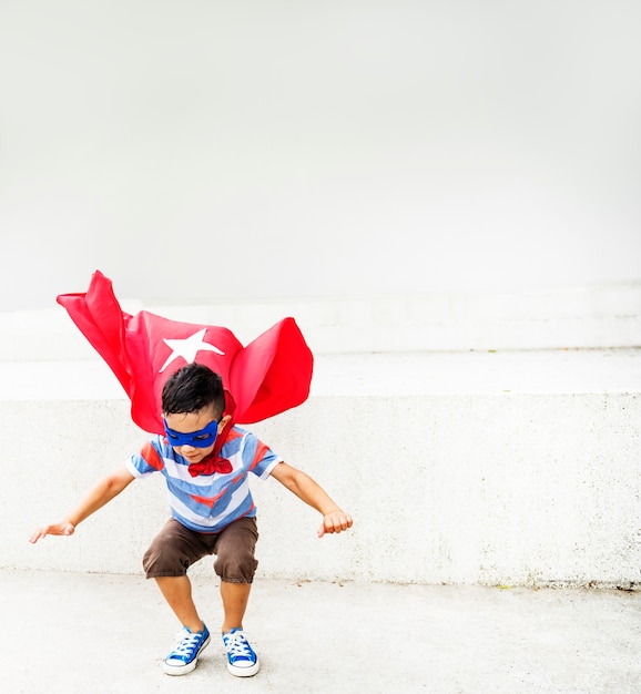 Kleiner Junge, der Superhelden am Spielplatz spielt