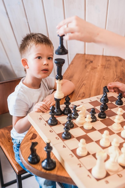 Kleiner Junge, der zu Hause am Tisch Schach spielt