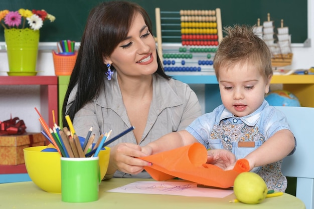 Kleiner Junge, der zu Hause oder im Kindergarten mit Mutter spielt