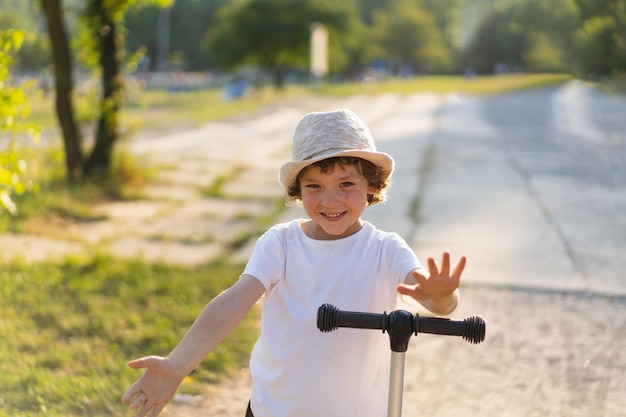 Kleiner Junge fährt an einem sonnigen Sommertag einen Roller Outdoor-Aktivität für Kinder Aktiver Sport für Kinder im Vorschulalter Kind auf Tretroller im Park