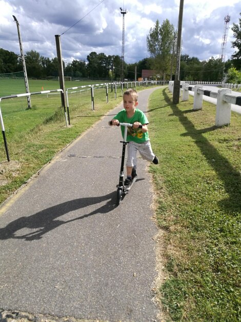 Foto kleiner junge fährt auf einem fußweg mit einem schubscooter