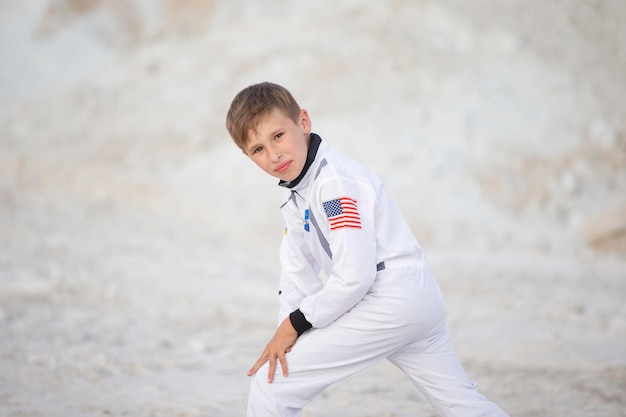 Kleiner Junge, gekleidet wie ein amerikanischer Astronaut, der vor dem Hintergrund der weißen Berge posiert