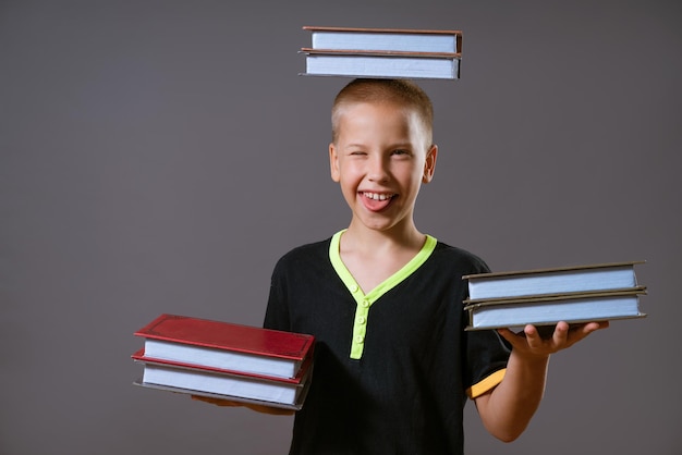 Foto kleiner junge hält die bücher in den händen und auf dem kopf