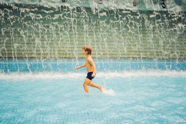 Kleiner Junge hat Spaß beim Laufen im Schwimmbad