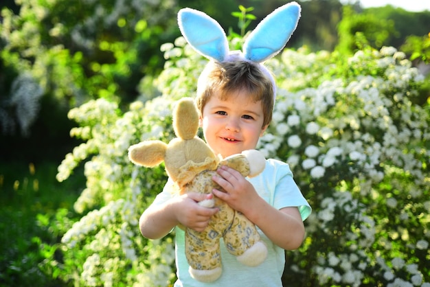 Kleiner Junge im grünen Wald Fröhliche Ostern Kindheit Eiersuche im Frühlingsurlaub Kaninchenkind mit Hasenohren Hasenspielzeugliebe Ostern Familienurlaub Frühlingsferien