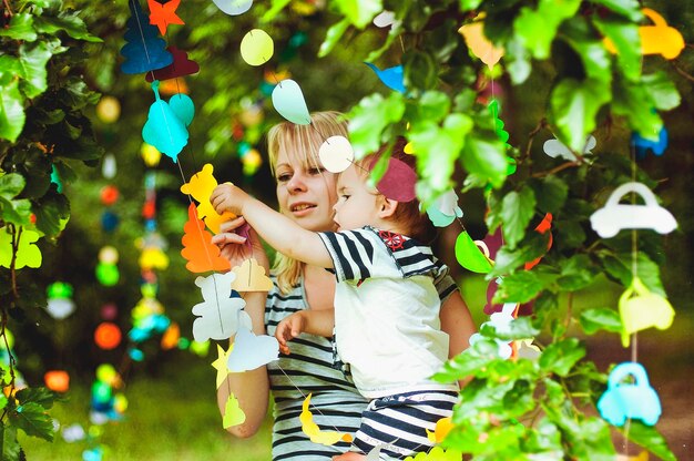 Kleiner Junge im Matrosenanzug, der auf Mutterhänden sitzt. Lachen. Sommer sonniger Tag. Alles Gute zum Geburtstag der Familie