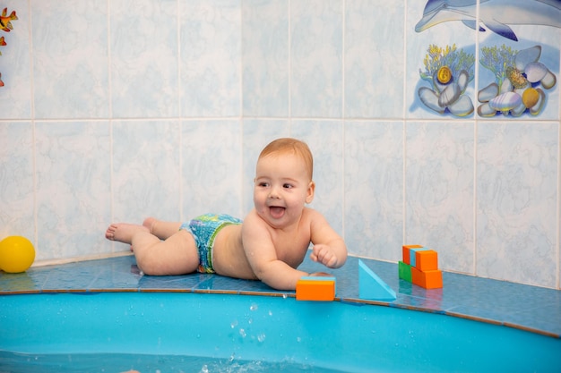 kleiner Junge im Pool, der mit Spielzeug in bunten Würfeln spielt