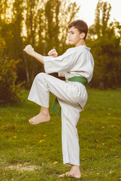 Kleiner Junge im weißen Kimono während des Trainings Karateübungen im Sommer im Freien