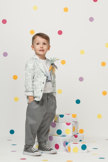 Kleiner Junge in den trendigen und Designer-Anzügen und Turnschuhen auf weißem Hintergrund