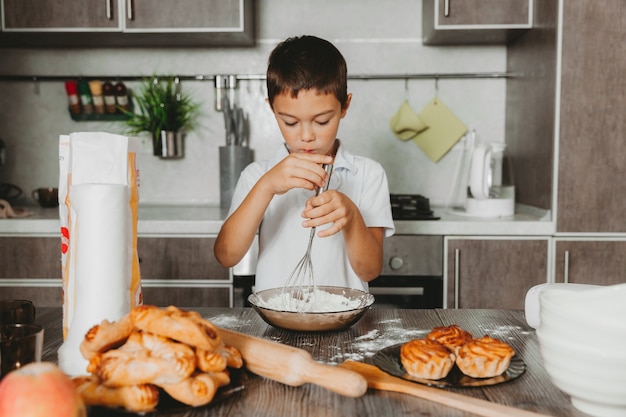 Kleiner Junge in der Küche, die Teig macht. Junge hilft Mama in der Küche.