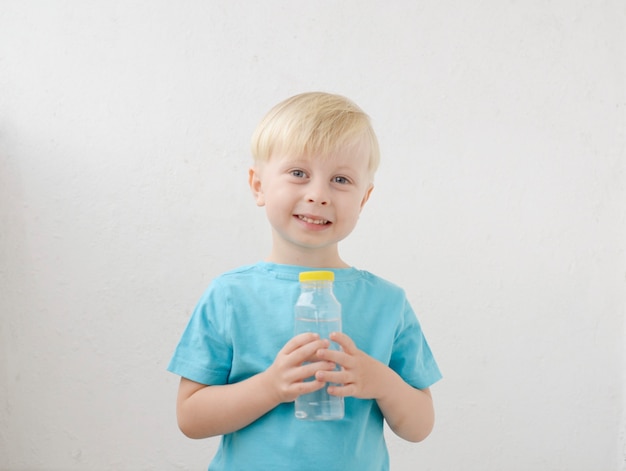 kleiner Junge in einem blauen T-Shirt trinkt Wasser