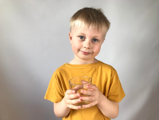 kleiner Junge in einem gelben T-Shirt trinkt Wasser