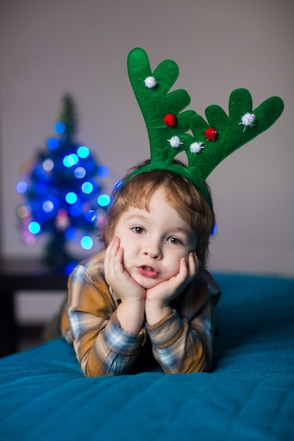 Foto kleiner junge in einem neujahrskostüm eines hirsches, der weihnachten und neujahr feiert
