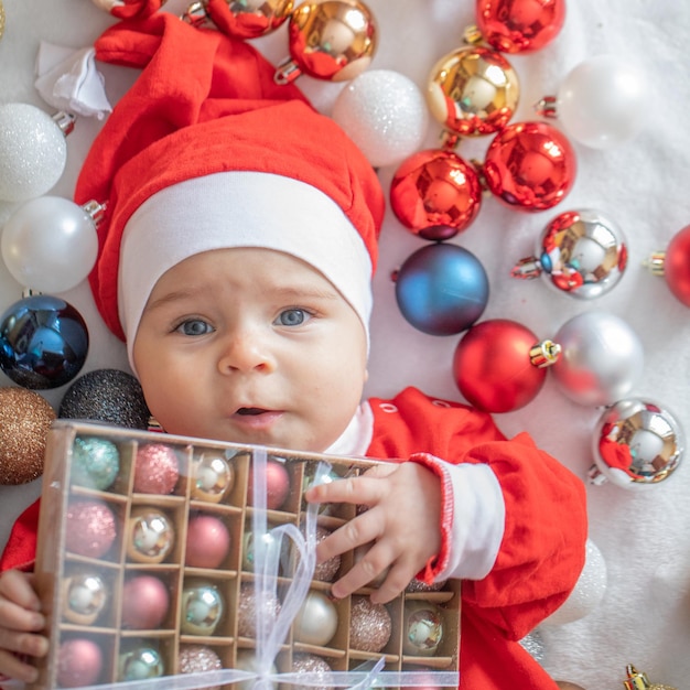 Kleiner Junge in einem Weihnachtsmann-Kostüm mit Weihnachtsschmuck.