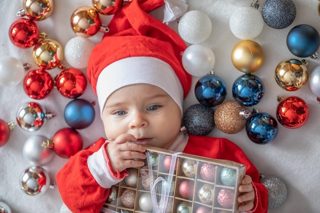 Kleiner Junge in einem Weihnachtsmann-Kostüm mit Weihnachtsschmuck.