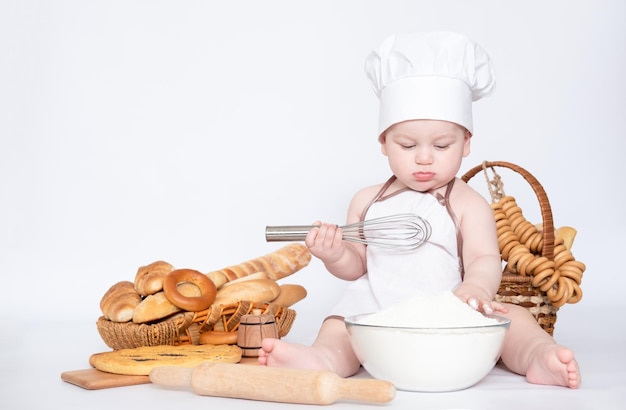 Kleiner Junge in einer Kochmütze und mit Brot lustiger kleiner Koch