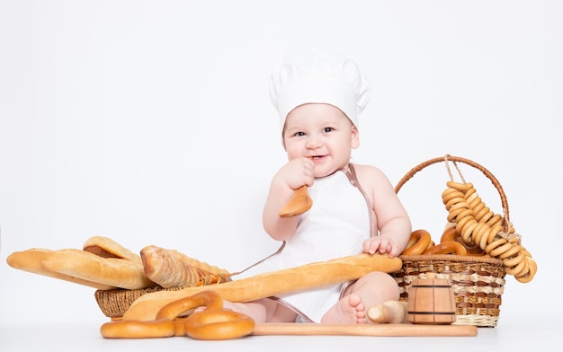 Kleiner Junge in einer Kochmütze und mit Brot lustiger kleiner Koch