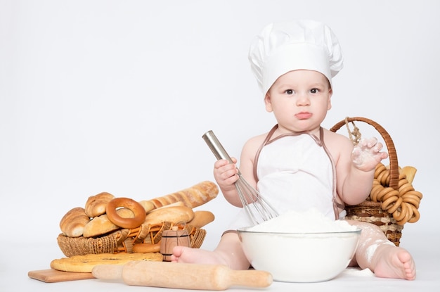 Kleiner Junge in einer Kochmütze und mit Brot lustiger kleiner Koch