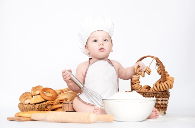 Kleiner Junge in einer Kochmütze und mit Brot lustiger kleiner Koch