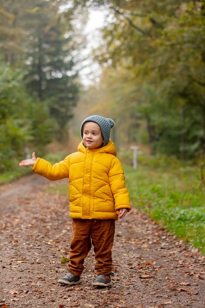 Kleiner Junge in gelber Jacke bleibt allein im Wald