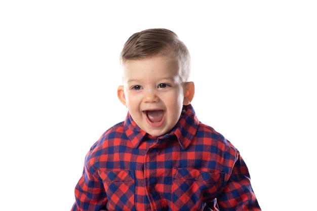 Kleiner Junge in stilvoller Freizeitkleidung, der über weißem Wandhintergrund lächelt