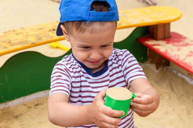 Kleiner Junge, Kind spielt im Sandkasten mit einer Schaufel und Schimmelpilzen