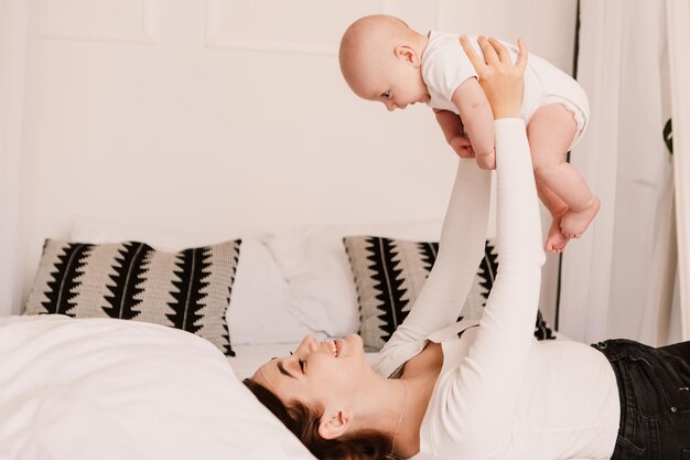 Kleiner Junge, lustiges, süßes Kind, Mutter, die mit dem Sohn spielt, wirft das Baby. Spielerisches lächelndes Lachen