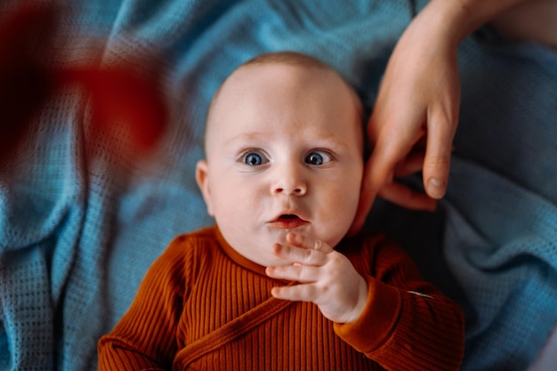 Kleiner Junge mit blauen Augen in der Krippe Mama streichelt den Jungen mit einem Finger auf seiner Wange