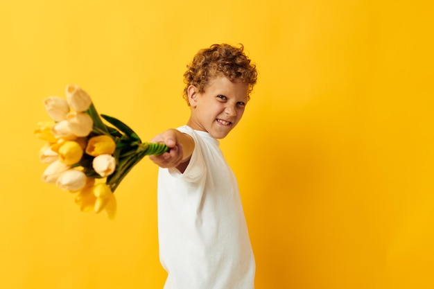 Kleiner Junge mit einem Blumenstrauß ein Geschenk gelben Hintergrund unverändert