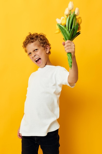 Kleiner Junge mit einem Blumenstrauß ein Geschenk gelben Hintergrund unverändert