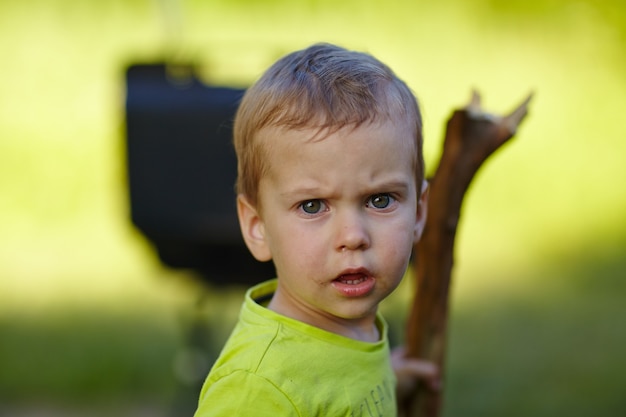 Kleiner Junge mit einem Stock in der Natur