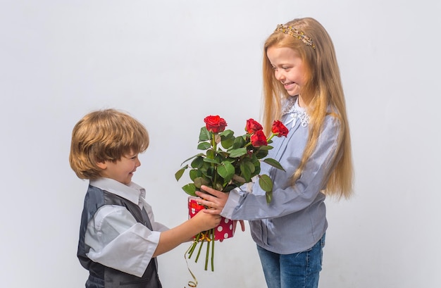 Kleiner Junge mit einer Rose für seine jugendlich Freundin romantische Kinder romantischer Junge und Mädchen, die einen Fluss geben