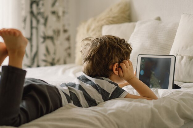 Kleiner Junge mit einer Tablette im Zimmer