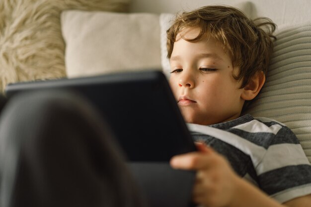 Kleiner Junge mit einer Tablette im Zimmer