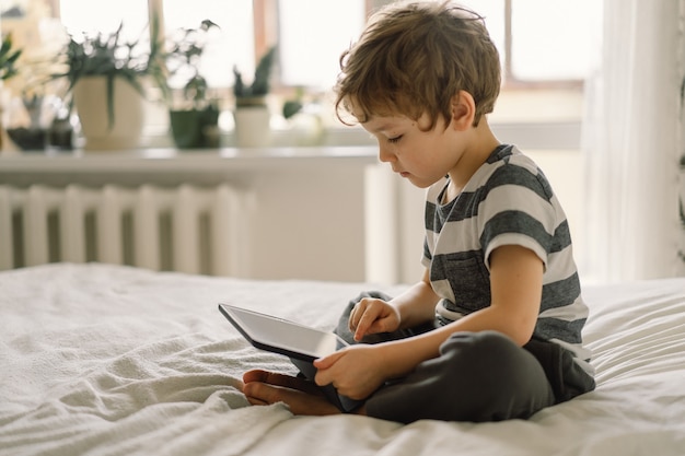 Kleiner Junge mit einer Tablette im Zimmer