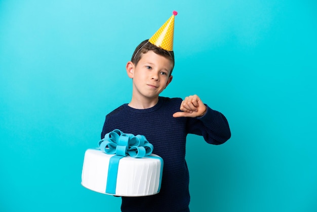 Kleiner Junge mit Geburtstagstorte isoliert auf blauem Hintergrund stolz und selbstzufrieden