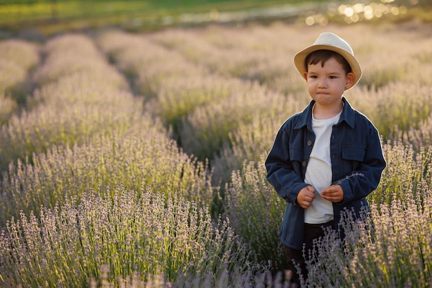 Kleiner Junge mit Hut auf einem Feld mit Lavendel