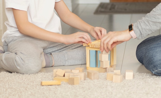 Kleiner Junge mit Mutter, die lacht, nachdem hoher Spielzeug-Holzblockturm fällt