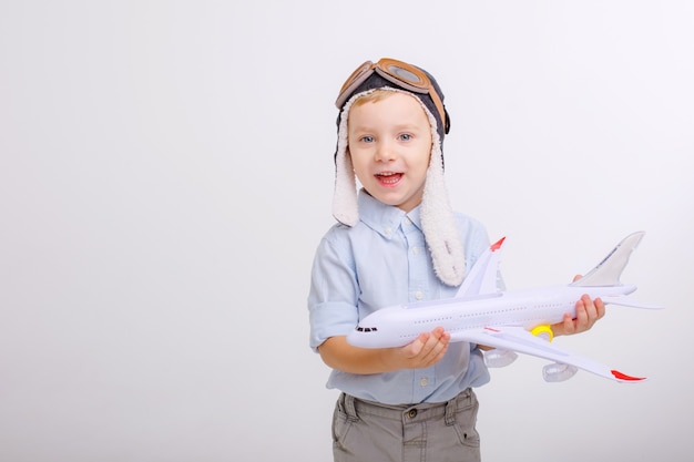 Kleiner Junge mit Pilotenmütze und mit einem Flugzeug auf weißem Hintergrund