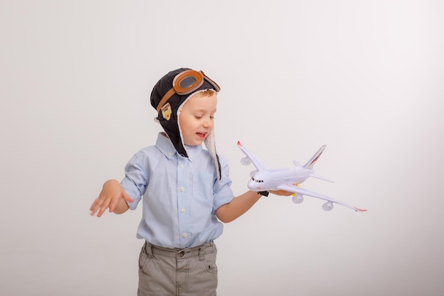 Kleiner Junge mit Pilotenmütze und mit einem Flugzeug auf weißem Hintergrund