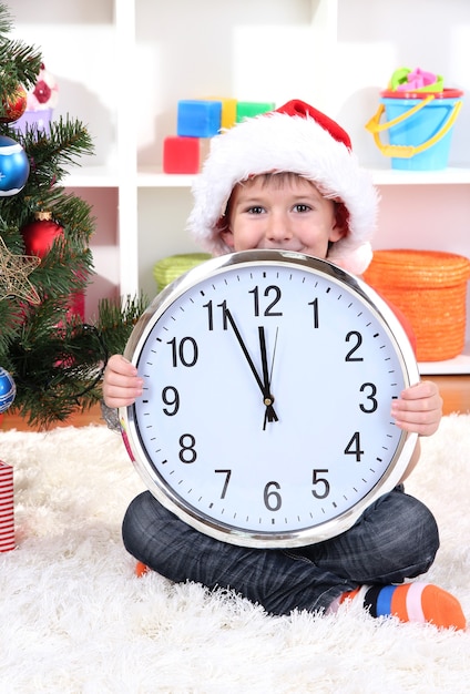 Kleiner Junge mit Uhr in Erwartung des neuen Jahres