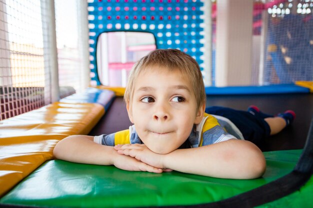 Kleiner Junge ruht auf Trampolin im Spielzentrum Glückliche Kindheit