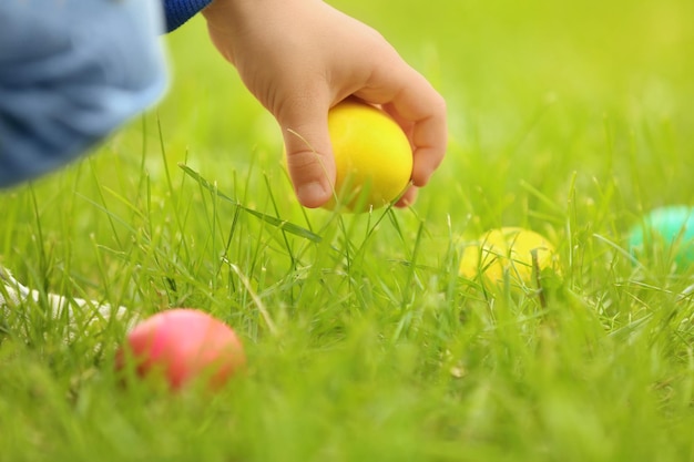 Kleiner Junge sammelt bunte Eier im Park Osterjagdkonzept