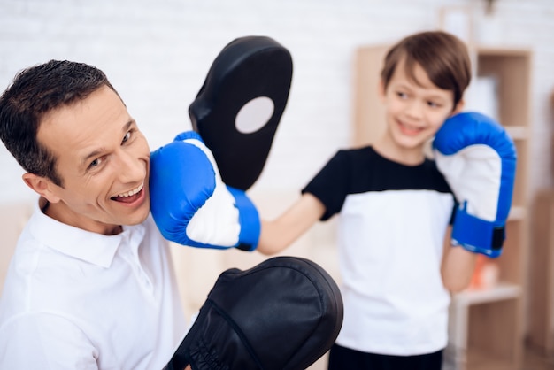 Foto kleiner junge schlägt vater in boxhandschuhen.