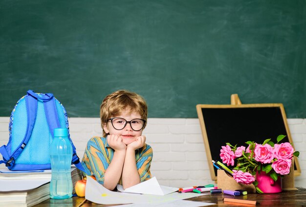 Kleiner Junge Schüler am Schreibtisch mit Schulmaterial Schuljunge an der Tafel Kind lernt in Klassenkindern